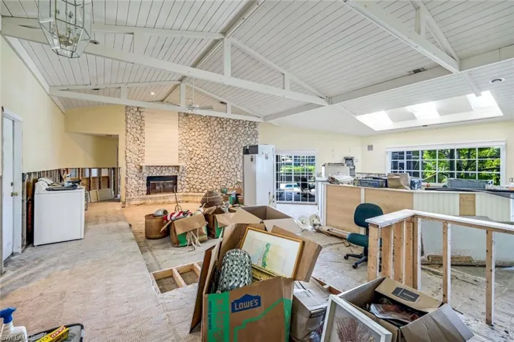Miscellaneous room featuring visible vents, high vaulted ceiling, a stone fireplace, and washer / dryer