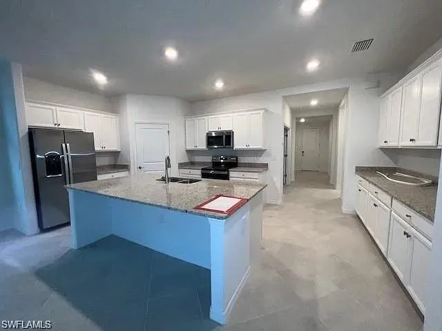 Kitchen with black appliances, a sink, recessed lighting, white cabinets, and a kitchen island with sink
