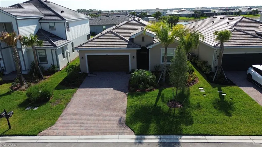 Single story home with an attached garage, stucco siding, decorative driveway, a tile roof, and a residential view