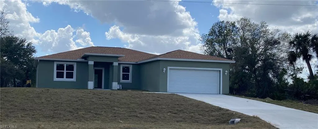 Contemporary stucco exterior with a two-car garage, concrete driveway, and brown shingle roof