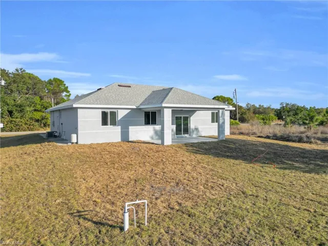 Back of property with roof with shingles, stucco siding, and a lawn