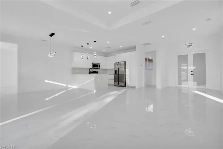 Unfurnished living room with light marble finish floors, recessed lighting, and french doors