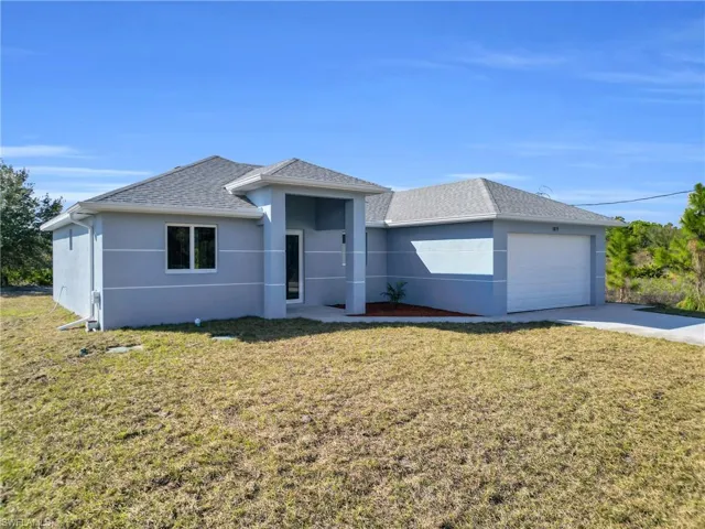 Single story home with a front lawn, stucco siding, roof with shingles, an attached garage, and driveway