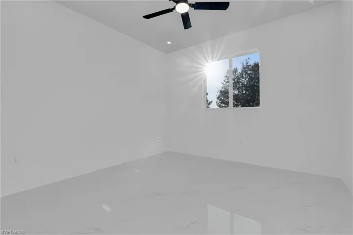 Empty room featuring a ceiling fan and marble finish flooring