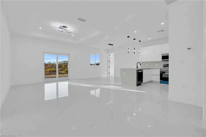 Unfurnished living room with recessed lighting, light marble finish floors, and a raised ceiling