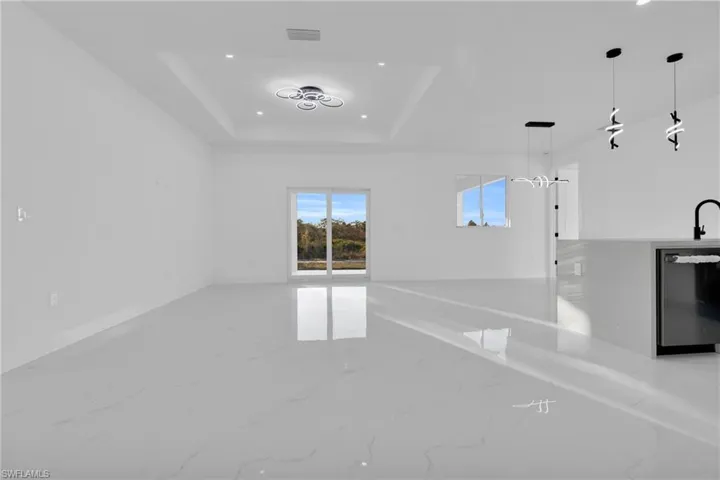 Unfurnished living room featuring light marble finish floors, recessed lighting, and a raised ceiling