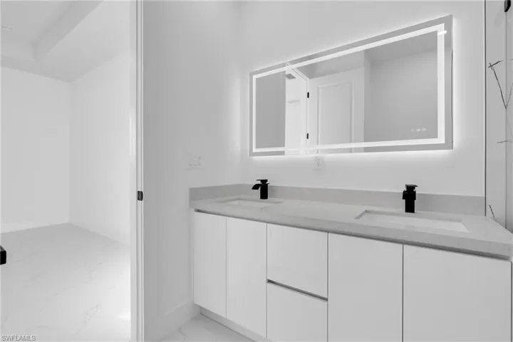 Full bathroom featuring double vanity and light marble finish floors
