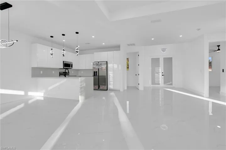 Kitchen with white cabinets, modern cabinets, a peninsula, pendant lighting, and open floor plan
