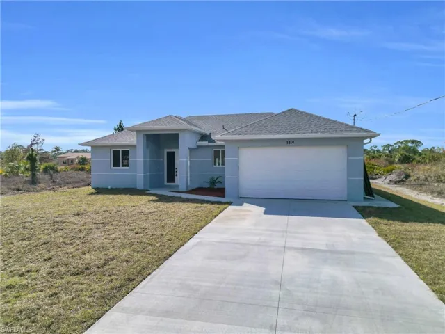 Ranch-style house featuring a front yard, stucco siding, driveway, and an attached garage