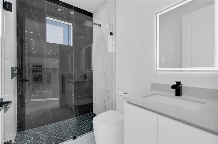 Bathroom featuring a marble finish shower and vanity
