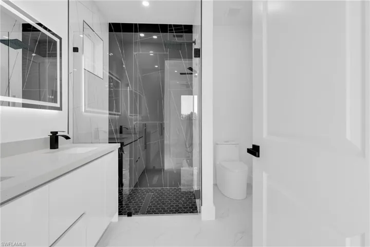 Bathroom featuring a marble finish shower, double vanity, recessed lighting, and light marble finish flooring