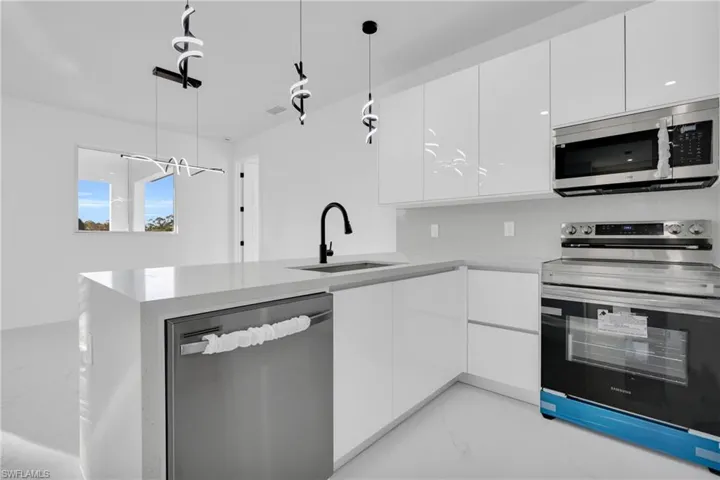 Kitchen with stainless steel appliances, white cabinets, a peninsula, and modern cabinets
