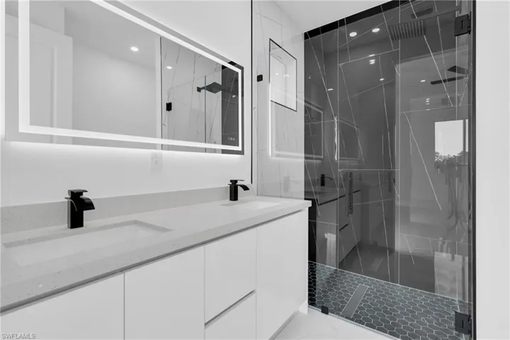 Full bath featuring a marble finish shower, double vanity, and recessed lighting