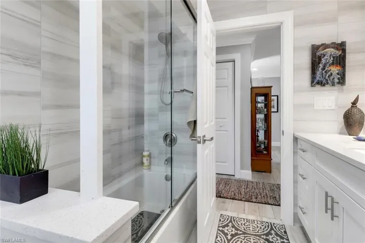 Bathroom with bath / shower combo with glass door and vanity