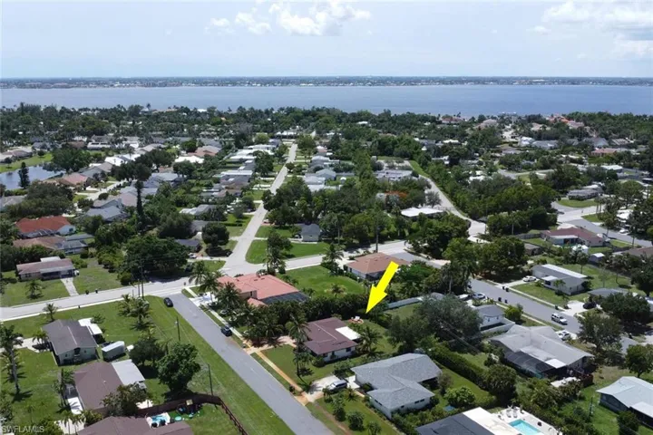 Aerial view of property and surrounding area featuring a nearby body of water and nearby suburban area