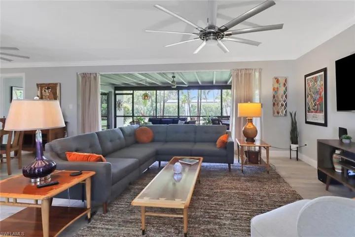 Living room featuring a ceiling fan, wood finished floors, and ornamental molding