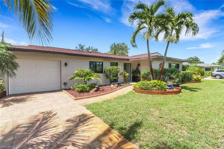 Ranch-style house with an attached garage, stucco siding, decorative driveway, and a front lawn