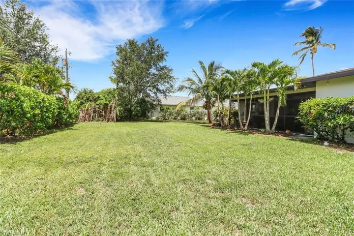 View of grassy yard with a sunroom