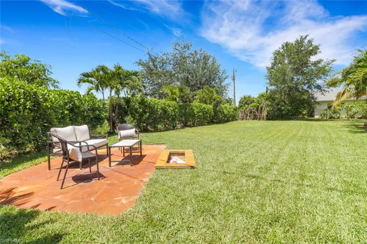 View of green lawn featuring a fire pit and a patio