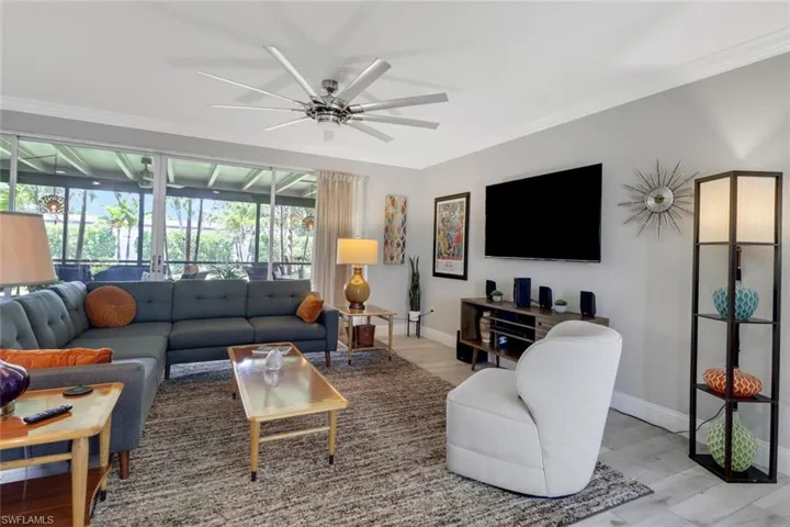 Living room with ceiling fan, light wood-style floors, and crown molding
