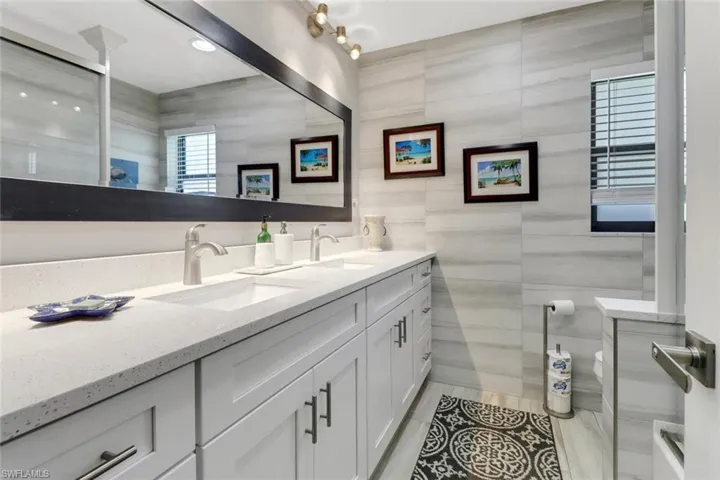 Bathroom featuring double vanity, tile walls, a shower, and tile patterned flooring