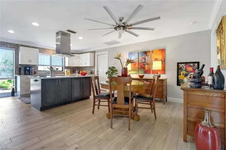 Dining room with crown molding, ceiling fan, light wood-style floors, and recessed lighting
