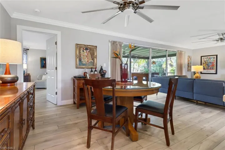 Dining room with ceiling fan, light wood finished floors, and ornamental molding