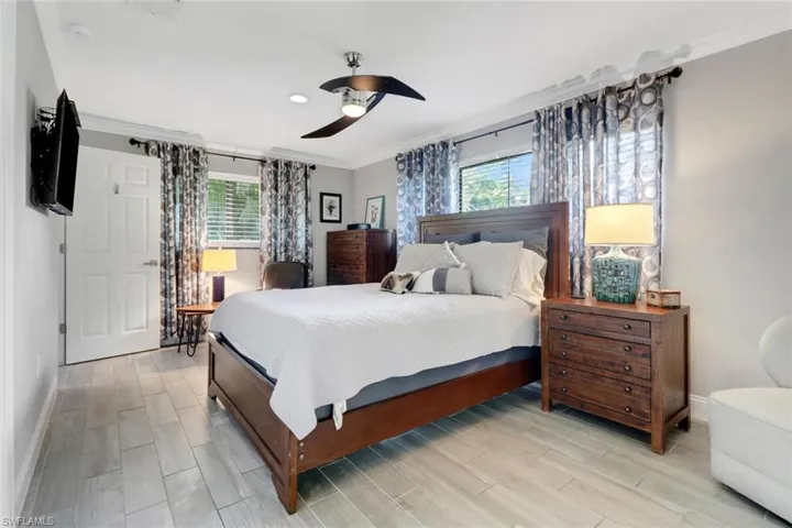 Bedroom featuring crown molding, multiple windows, light wood-type flooring, and a ceiling fan