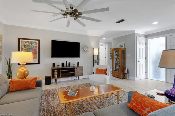 Living room featuring ornamental molding, light wood-style flooring, ceiling fan, and recessed lighting