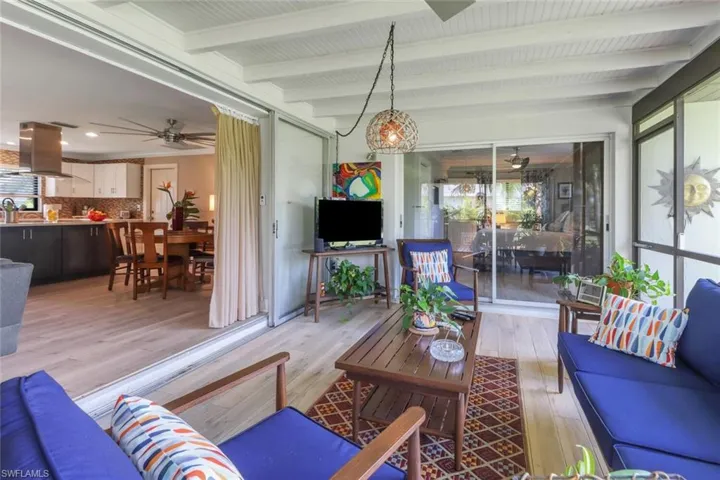 Living room featuring plenty of natural light, a ceiling fan, light wood-style flooring, and beamed ceiling