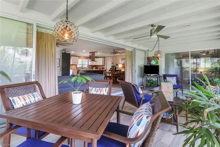 Dining space with a ceiling fan, light wood-style flooring, a chandelier, and beamed ceiling