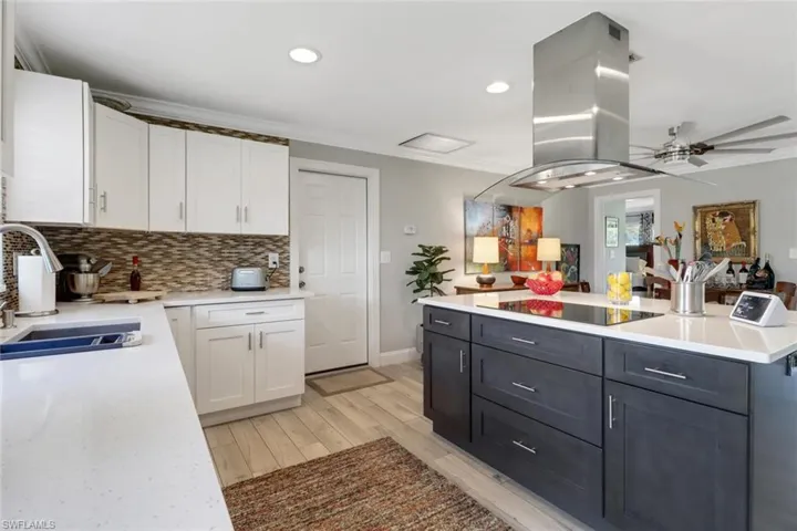 Kitchen featuring white cabinets, black electric stovetop, light countertops, recessed lighting, and ornamental molding