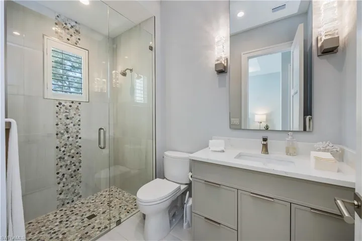 Bathroom featuring tile patterned flooring, vanity, an enclosed shower, and toilet