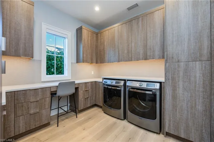 Laundry area with cabinets, washing machine and dryer, and light wood-type flooring