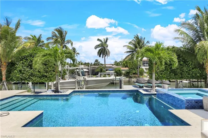 View of swimming pool featuring a water view and an in ground hot tub