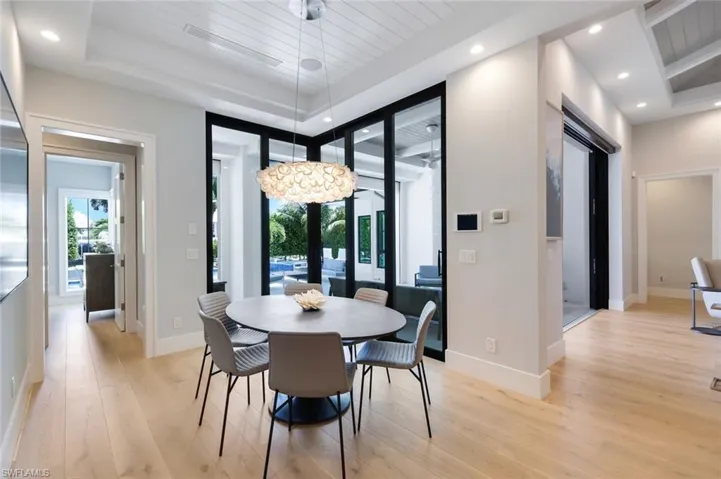 Dining space featuring a tray ceiling, light hardwood / wood-style floors, and wooden ceiling