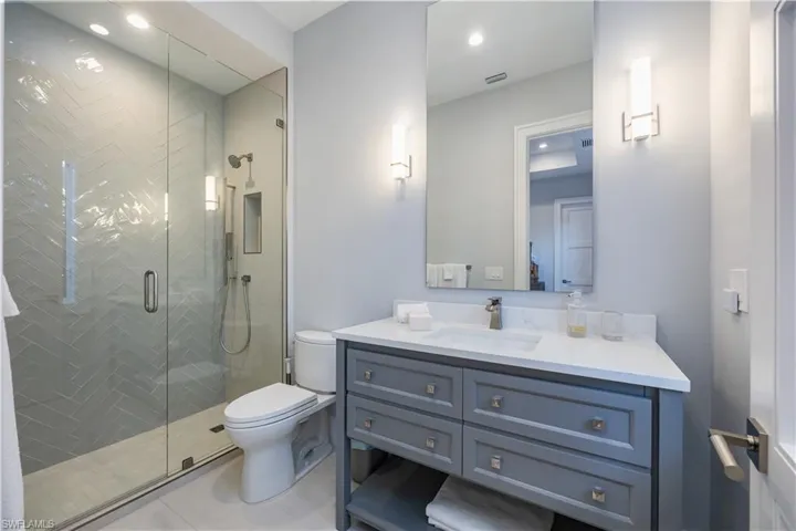Bathroom featuring tile patterned floors, vanity, toilet, and a shower with door