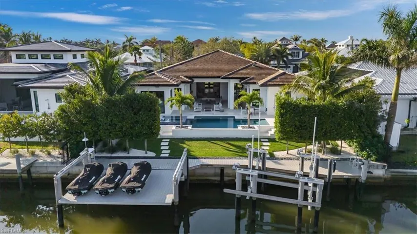 View of dock with a water view, a patio area, and a lawn