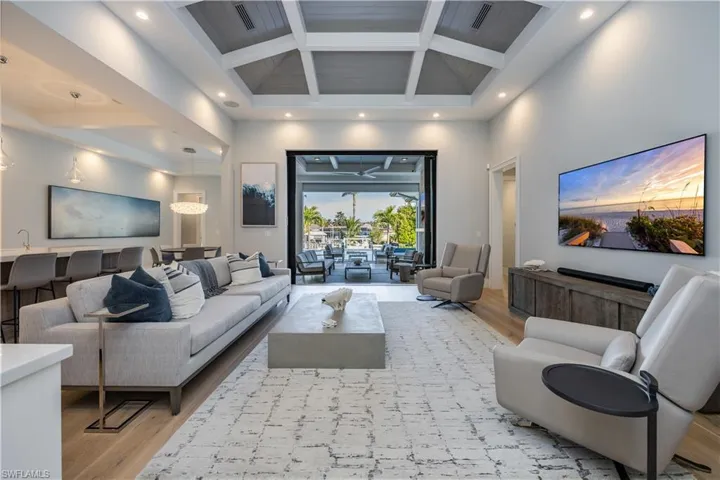 Living room with beamed ceiling, a towering ceiling, coffered ceiling, and light hardwood / wood-style floors