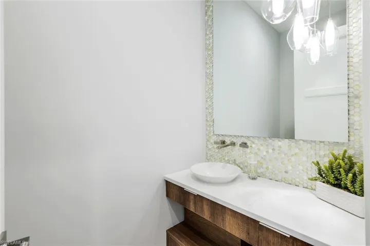 Bathroom with tasteful backsplash, vanity, and a notable chandelier
