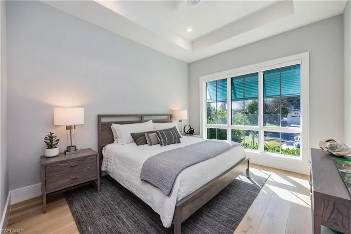 Bedroom with a tray ceiling and light wood-type flooring