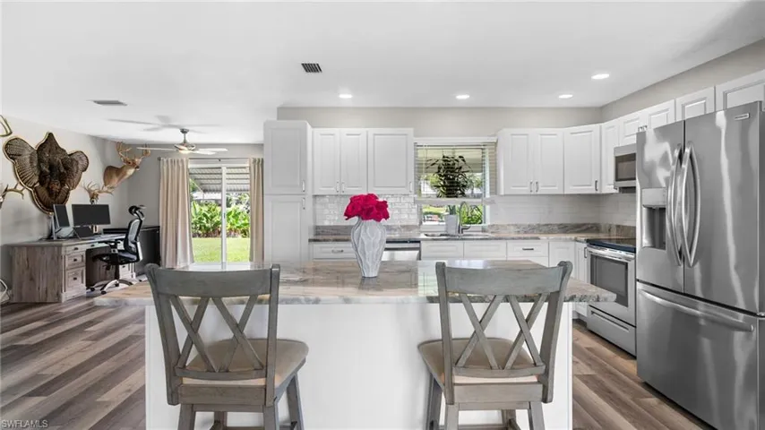 Kitchen with appliances with stainless steel finishes, hardwood / wood-style flooring, decorative backsplash, and white cabinets