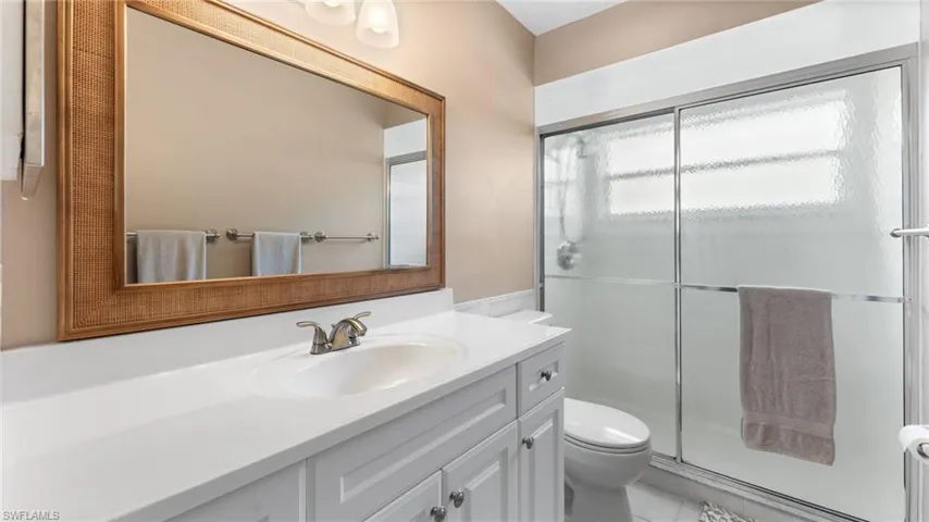 Bathroom featuring tile patterned flooring, toilet, vanity, and walk in shower