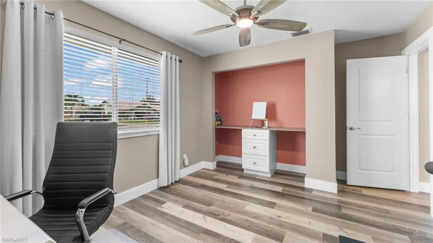 Unfurnished office with ceiling fan, wood-type flooring, and built in desk
