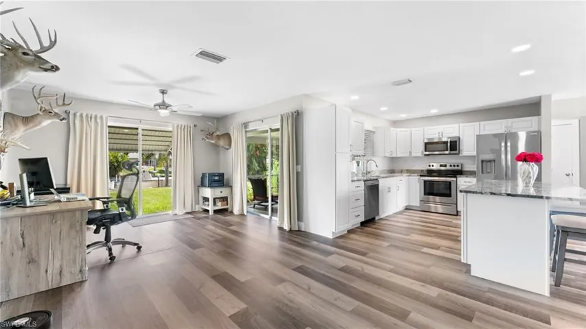 Kitchen featuring light hardwood / wood-style flooring, light stone countertops, a breakfast bar area, stainless steel appliances, and white cabinets