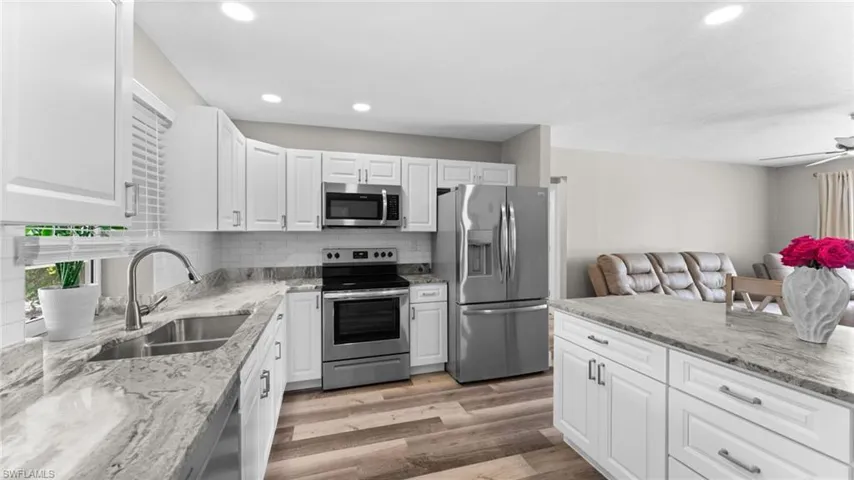 Kitchen with stainless steel appliances, light hardwood / wood-style flooring, white cabinetry, tasteful backsplash, and ceiling fan