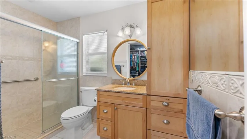Bathroom with tile patterned flooring, a shower with door, toilet, and vanity