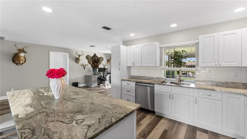 Kitchen with white cabinetry, backsplash, hardwood / wood-style flooring, and dishwasher