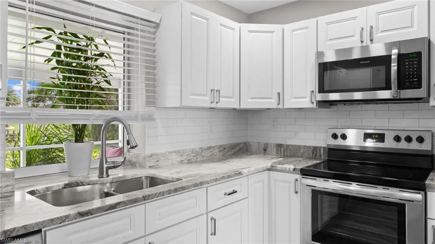 Kitchen with sink, white cabinetry, and appliances with stainless steel finishes