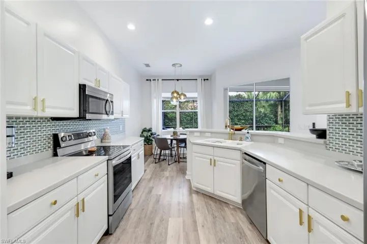 Kitchen featuring tasteful backsplash, appliances with stainless steel finishes, recessed lighting, white cabinetry, and light wood finished floors
